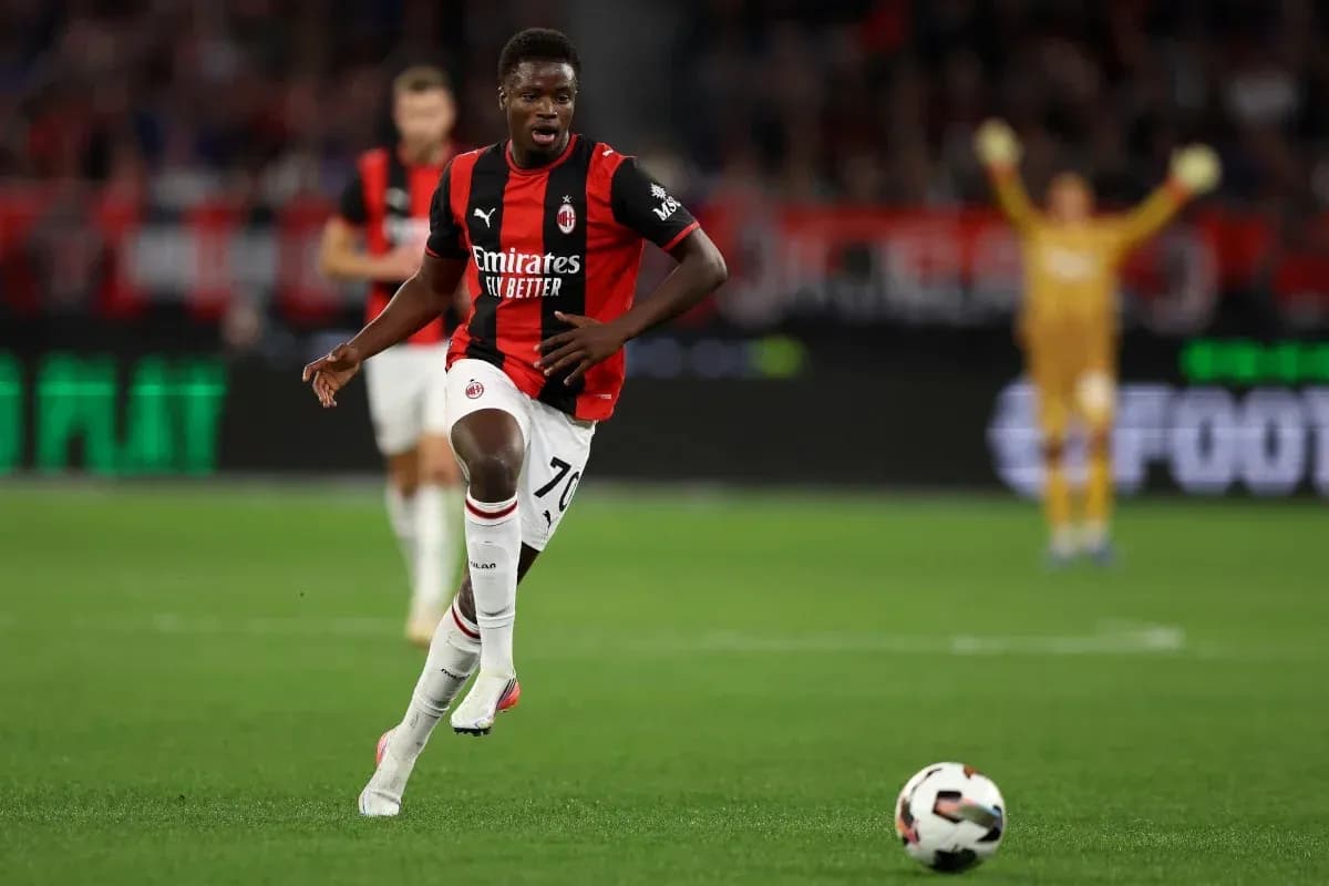 Player in AC Milan kit running with soccer ball