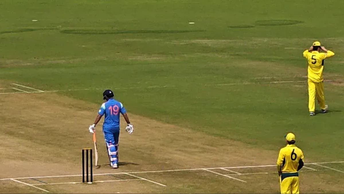 Batsman in blue uniform walking towards crease