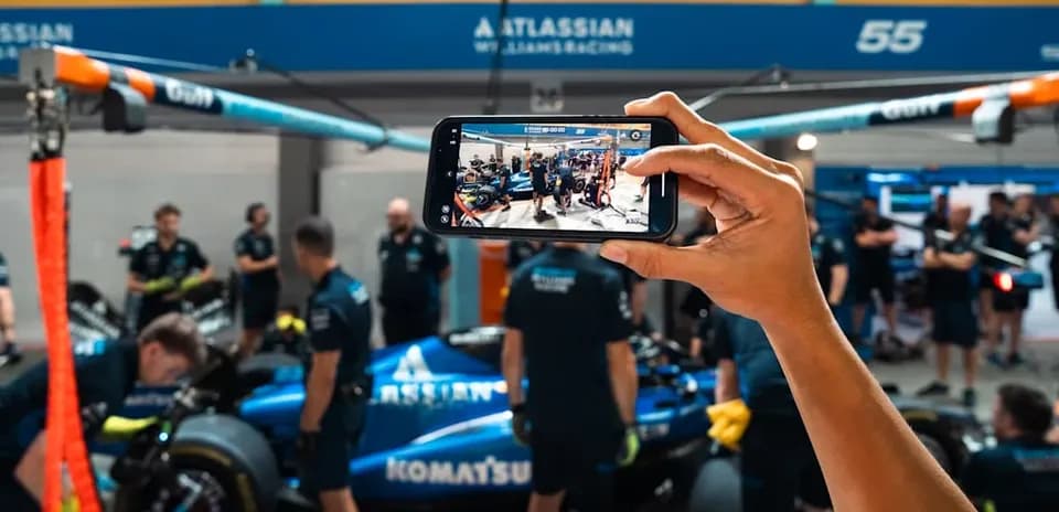 Team working on car in garage, phone capturing moment