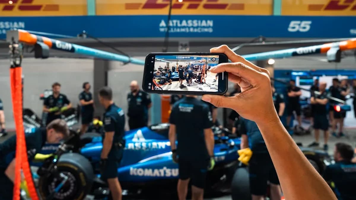 Team working on car in garage, phone capturing moment