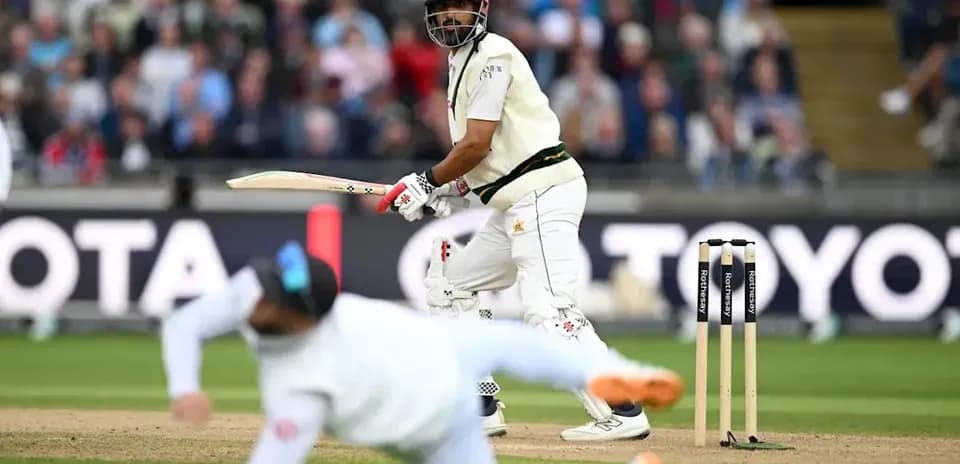 Batsman playing a shot while fielder dives nearby