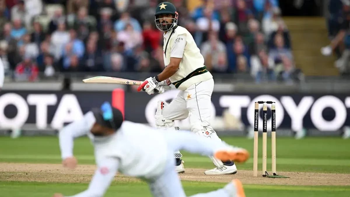Batsman playing a shot while fielder dives nearby