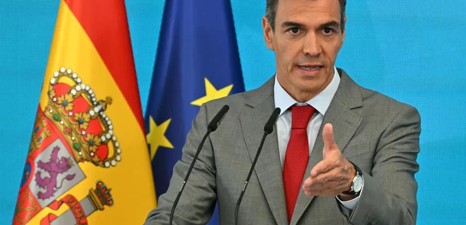 Politician speaking at a podium with flags behind