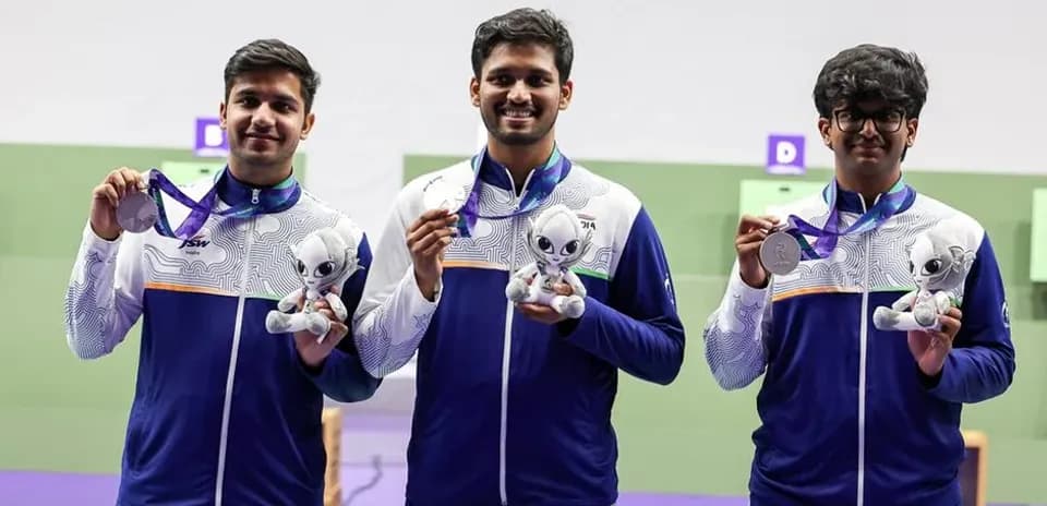 Three athletes holding medals and mascots on podium