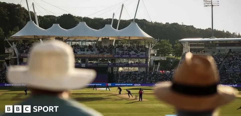 View of cricket match with spectators in foreground