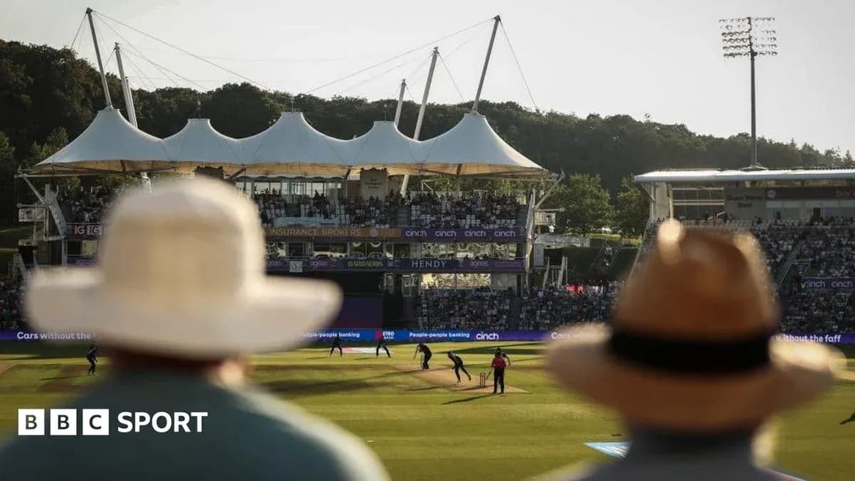 View of cricket match with spectators in foreground