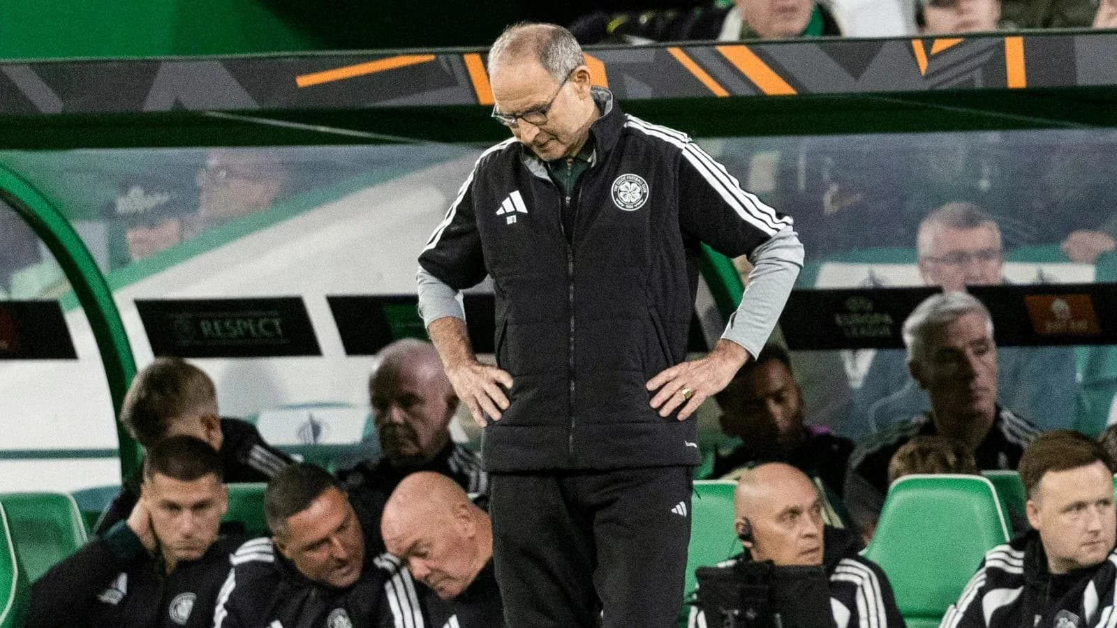 Coach looking down while team sits on bench Coach looking down while team sits on bench