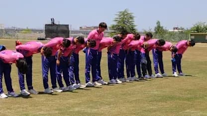 Cricket team bowing in unison on field
