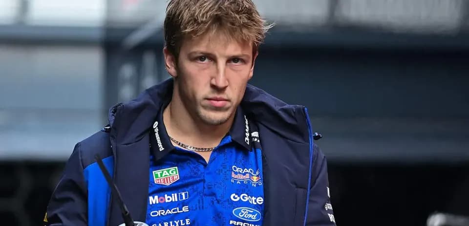 Driver in team jacket holding a drink