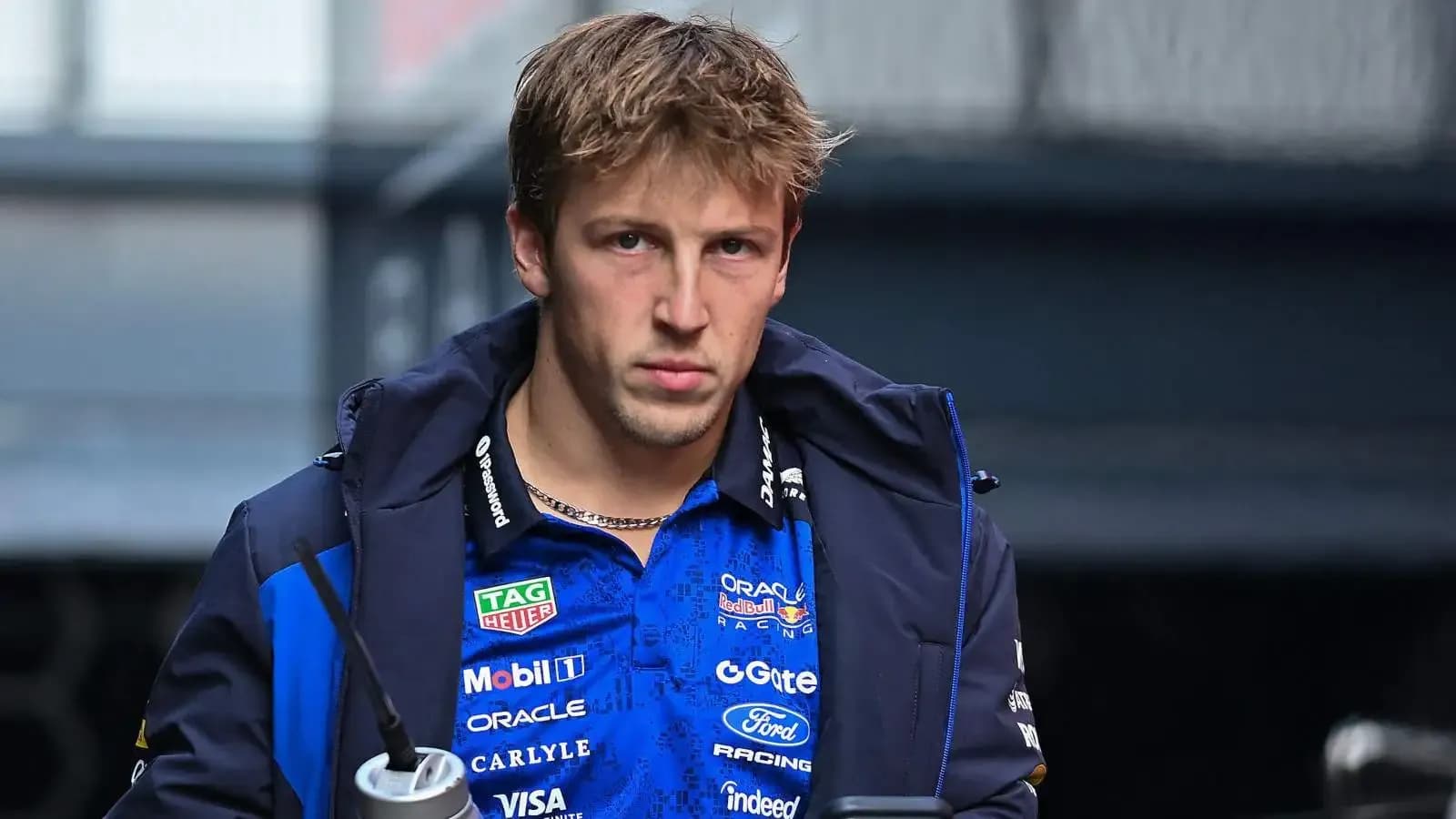 Driver in team jacket holding a drink