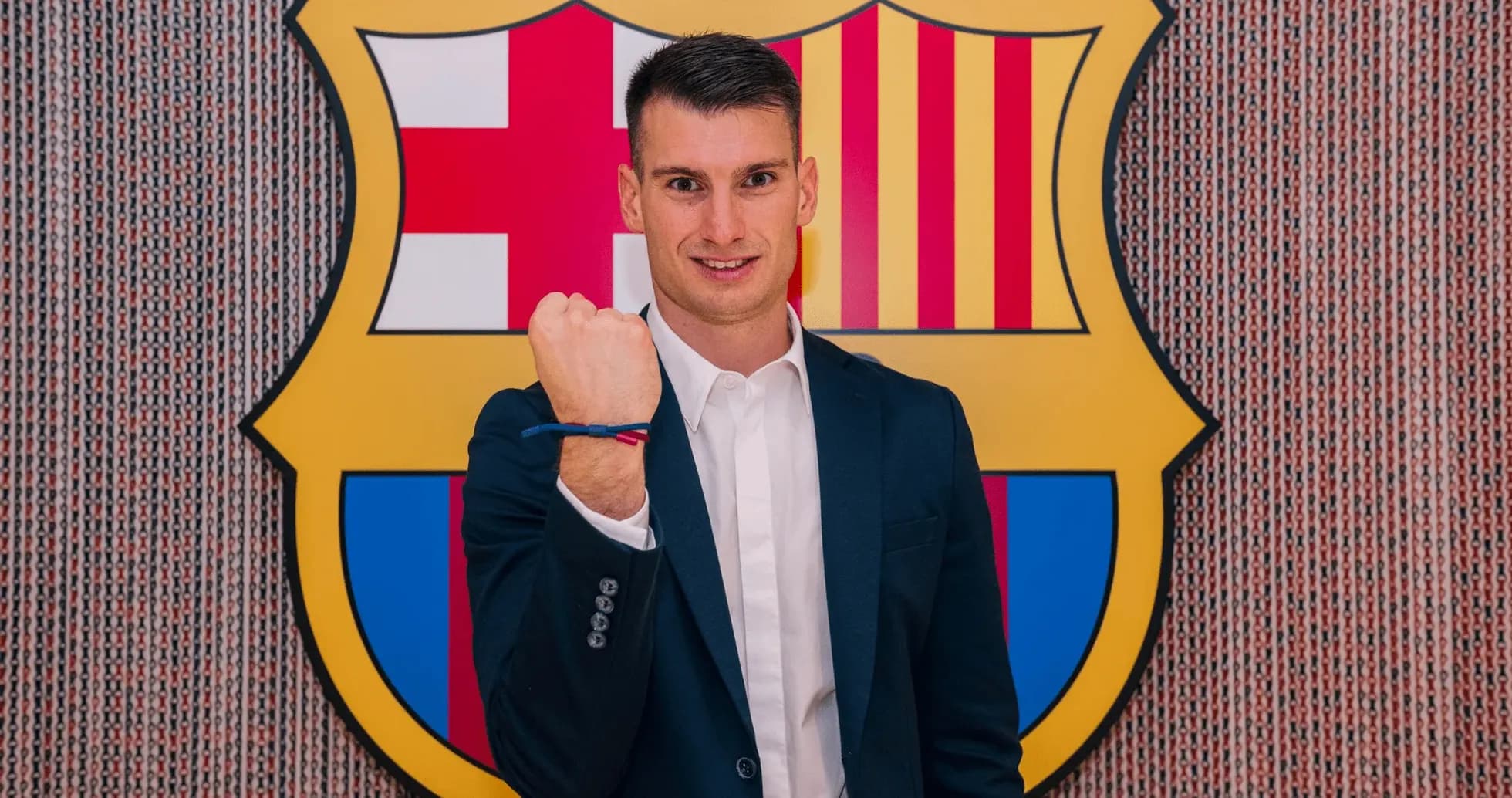 Player posing with fist raised in front of Barcelona logo