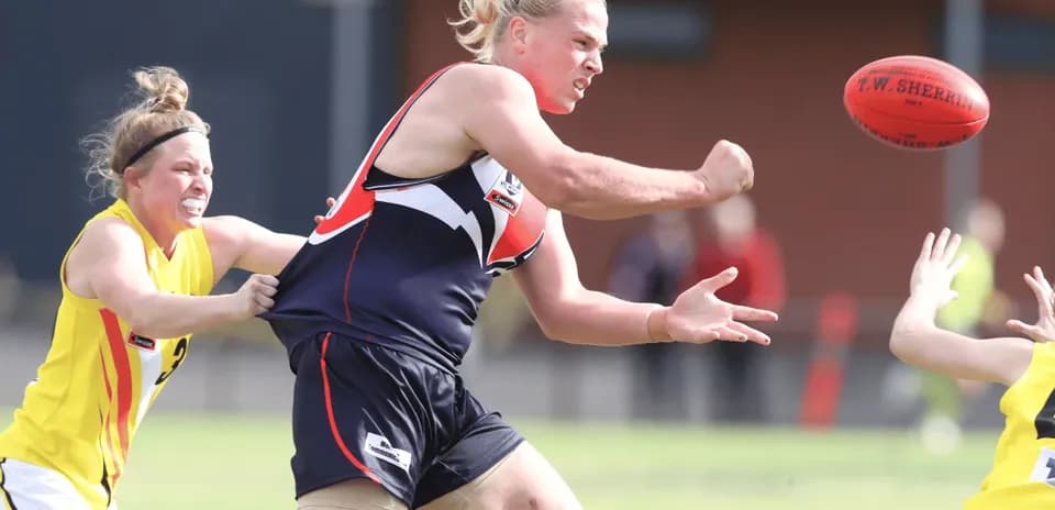 Player throwing the ball while being tackled during match