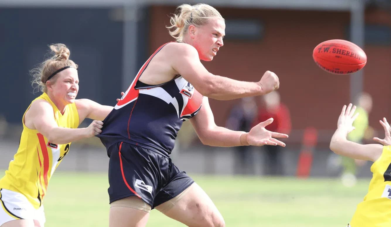 Player throwing the ball while being tackled during match