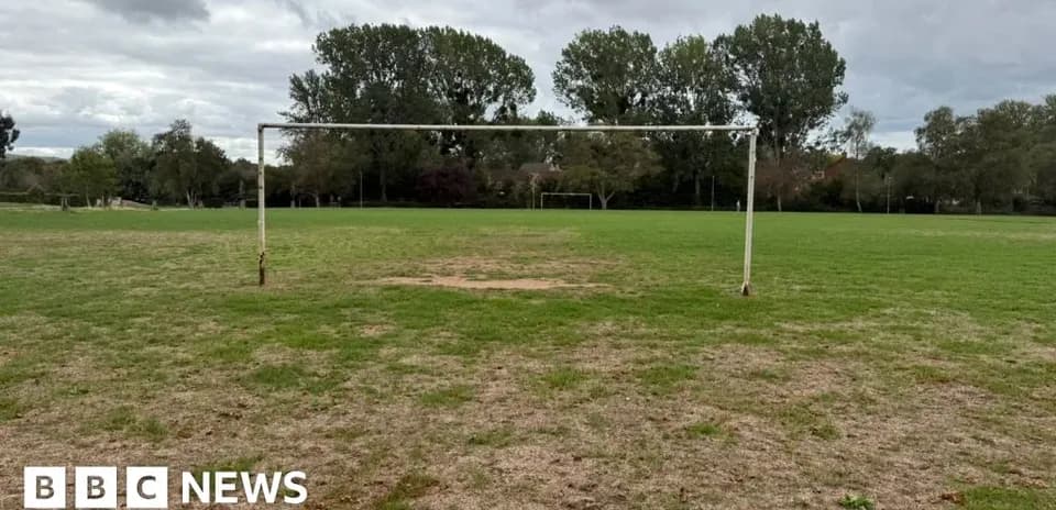 Empty soccer goal on grassy field under cloudy sky