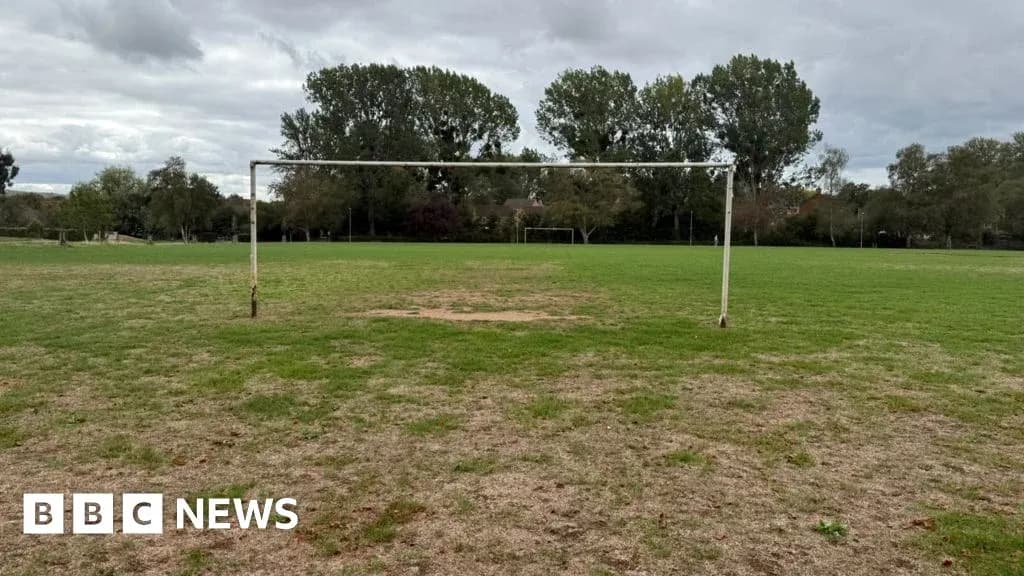 Empty soccer goal on grassy field under cloudy sky