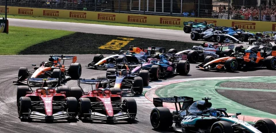 Multiple Formula 1 cars racing around a corner