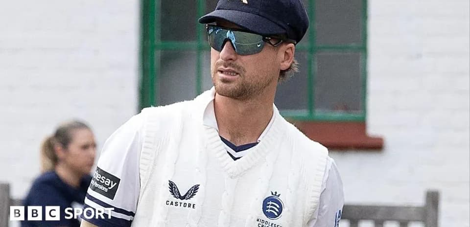Cricketer in Middlesex kit walking on field