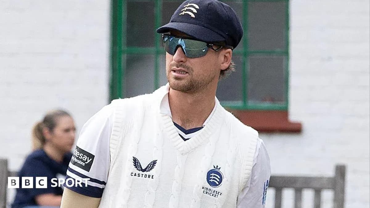 Cricketer in Middlesex kit walking on field