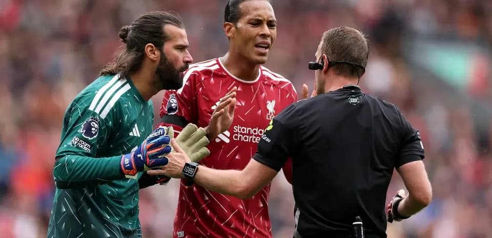 Goalkeeper and player discussing with referee during match