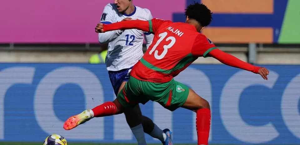 Player in red challenging opponent in blue for the ball