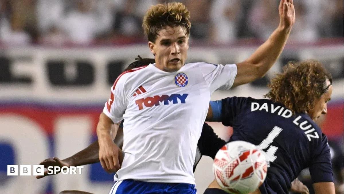Player in white jersey challenged by opponent Player in white jersey challenged by opponent