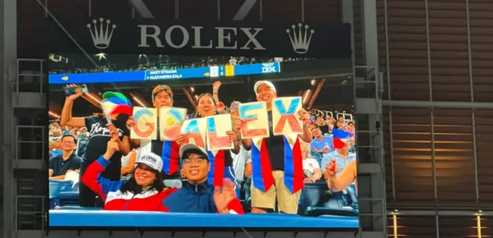 Fans cheering and holding 'GO ALEX' signs