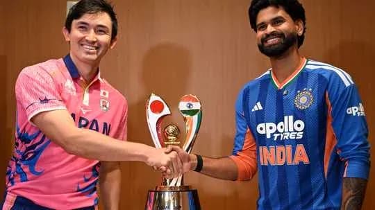 Players from Japan and India shaking hands by trophy