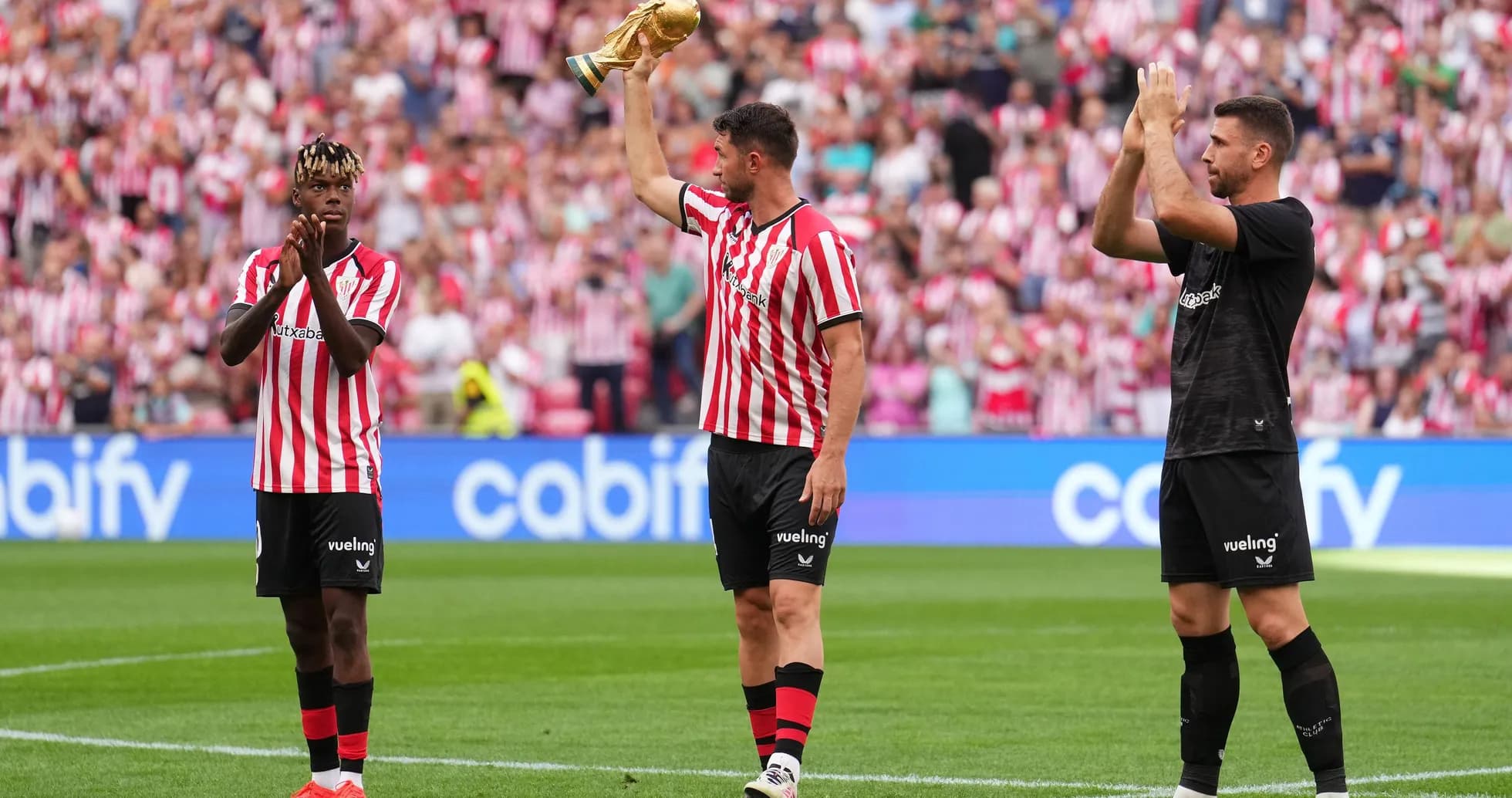 Athletic Bilbao players celebrating with trophy on pitch