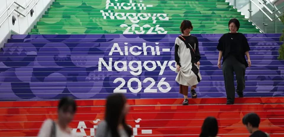 Two people walking down colorful steps labeled Aichi-Nagoya 2026