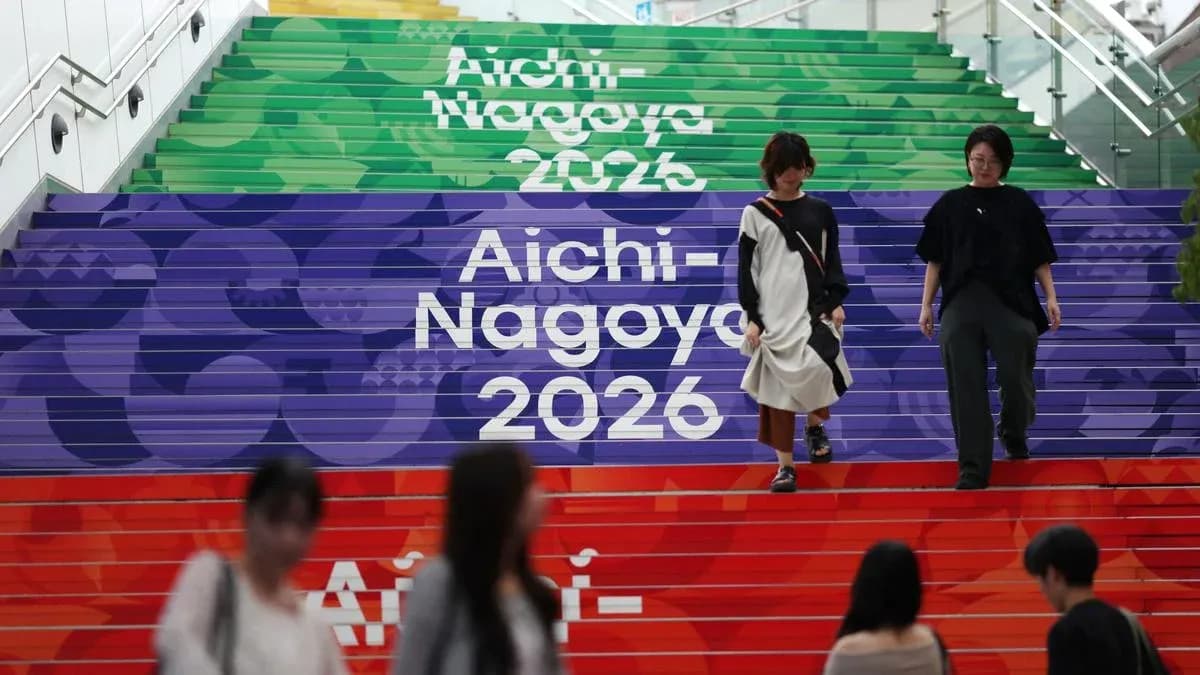 Two people walking down colorful steps labeled Aichi-Nagoya 2026