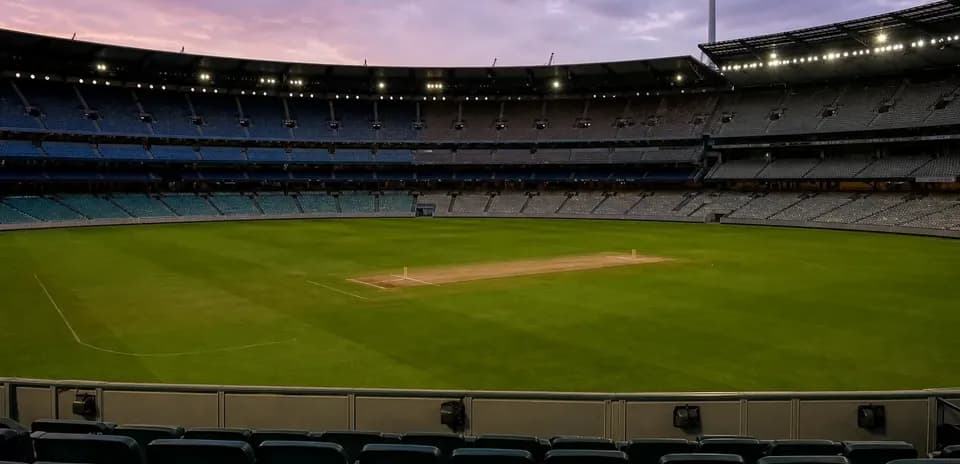 Empty cricket stadium field at dusk