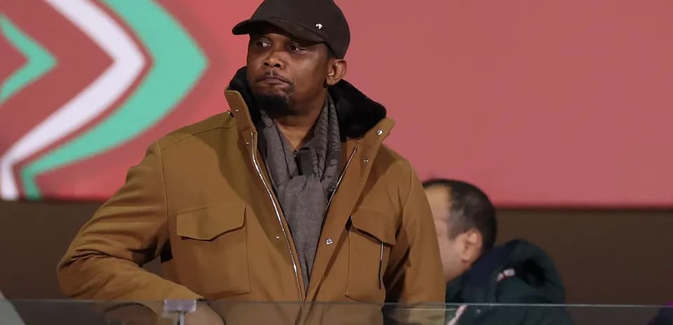 Man in brown coat observing event from VIP area