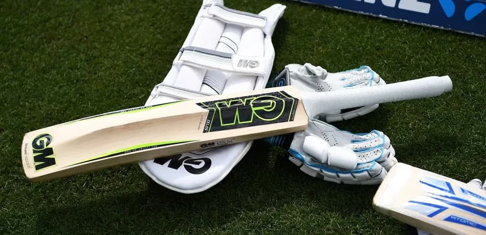 Cricket bat, gloves, and pads on grass