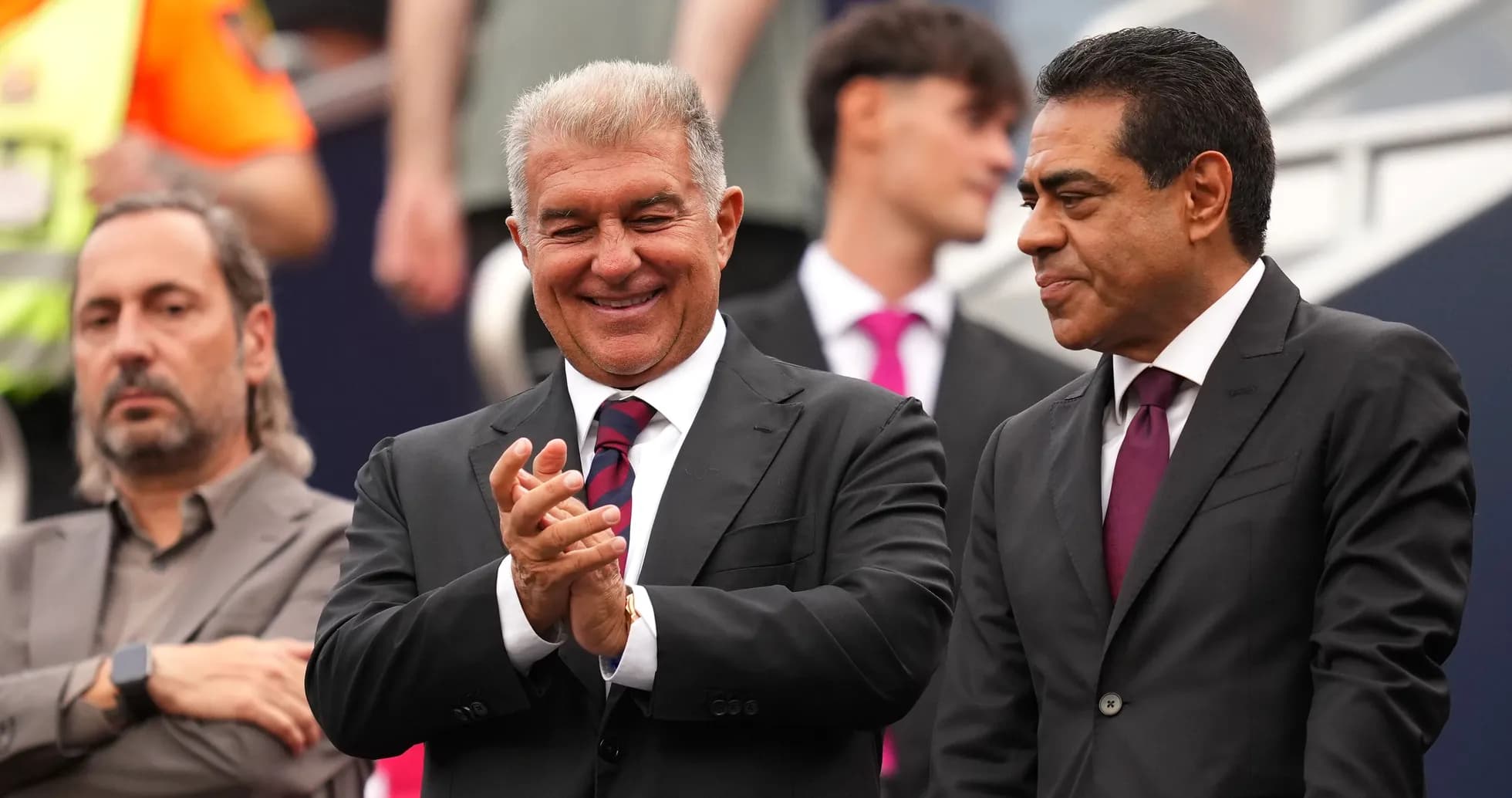 Three individuals in suits at a sporting event Three individuals in suits at a sporting event