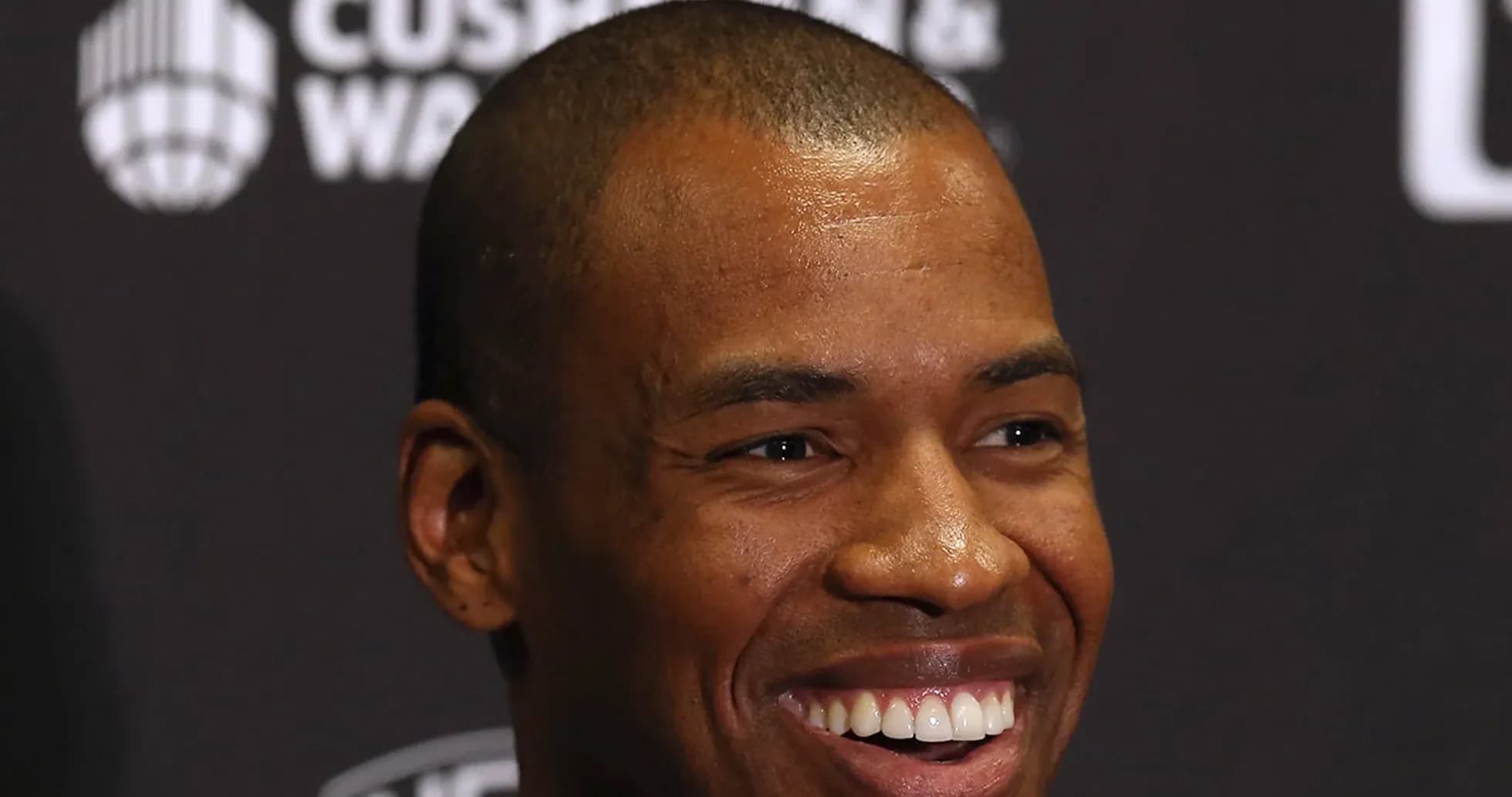 Person smiling at a press conference backdrop Person smiling at a press conference backdrop