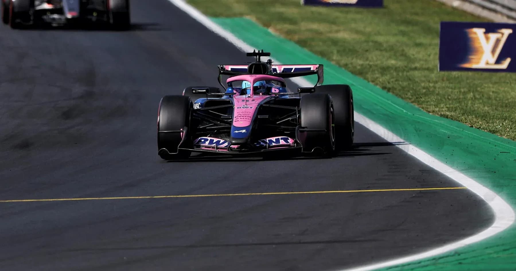 Formula 1 car racing on track with green curbing Formula 1 car racing on track with green curbing