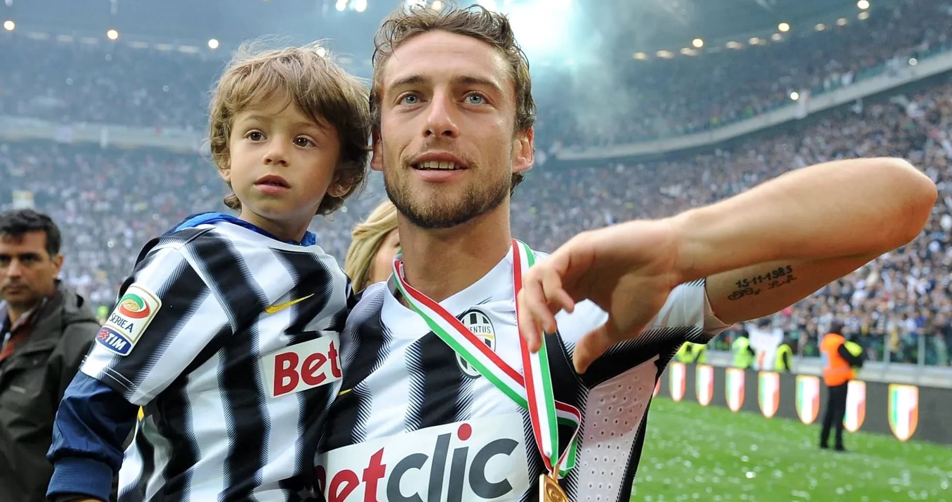 Player celebrating with child and medal on field Player celebrating with child and medal on field