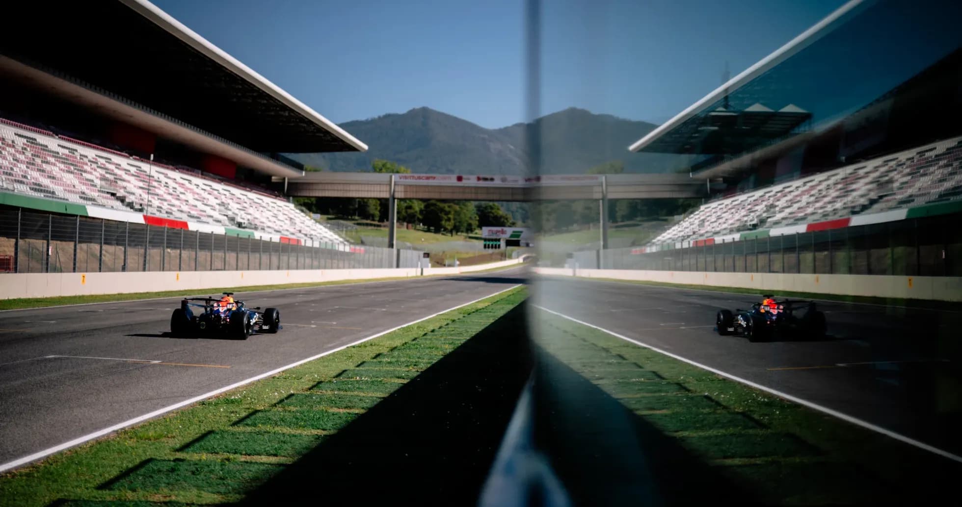 Race car driving on track with grandstand in background Race car driving on track with grandstand in background