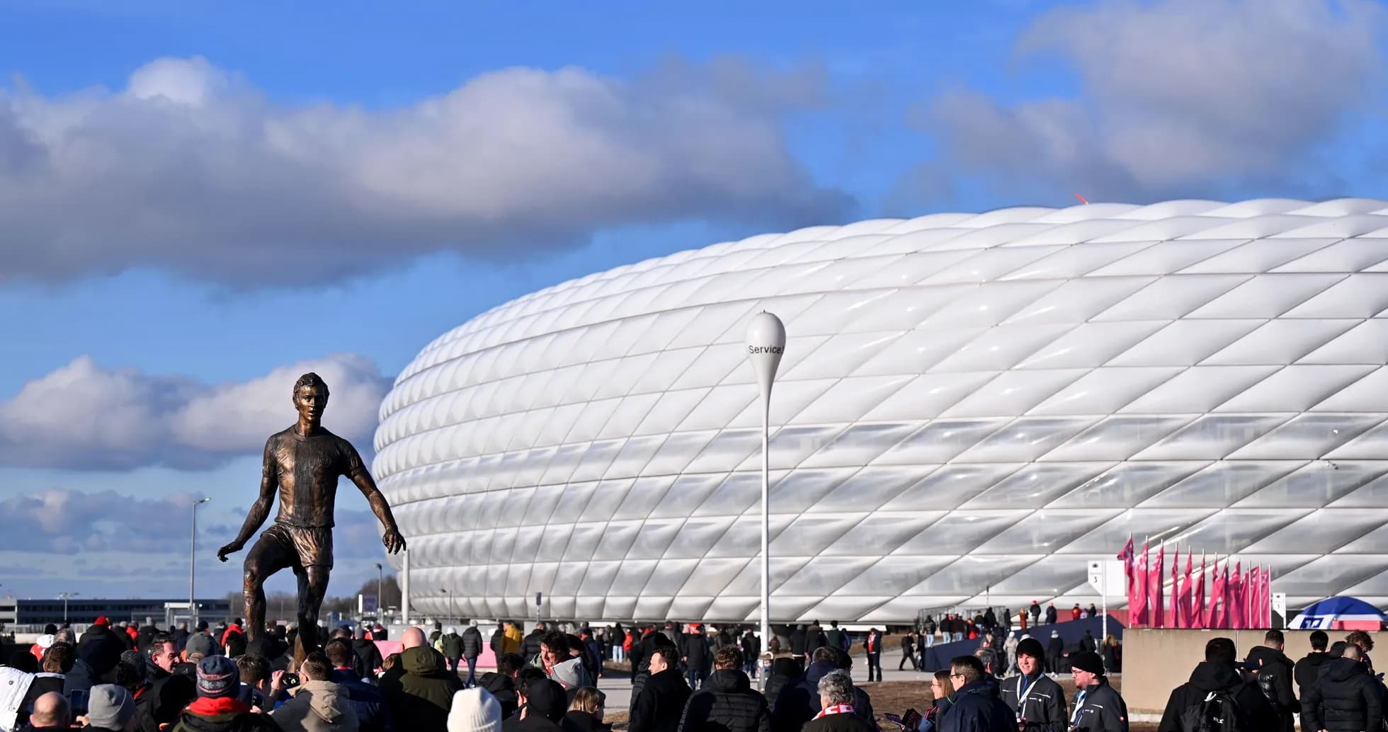 Crowd gathering outside stadium with statue Crowd gathering outside stadium with statue