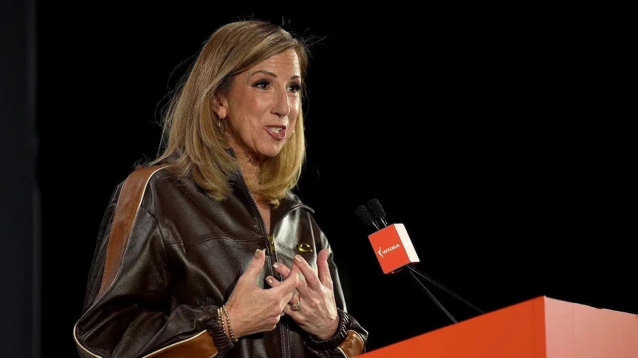 Woman speaking at a podium with WNBA logo Woman speaking at a podium with WNBA logo