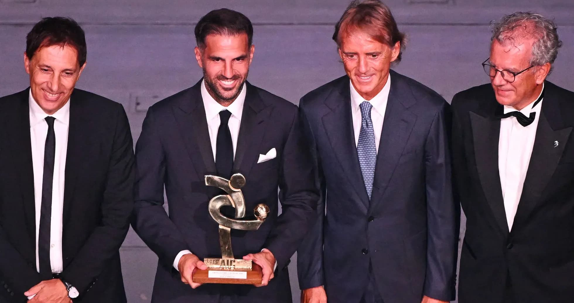 Four men posing with an award at ceremony Four men posing with an award at ceremony