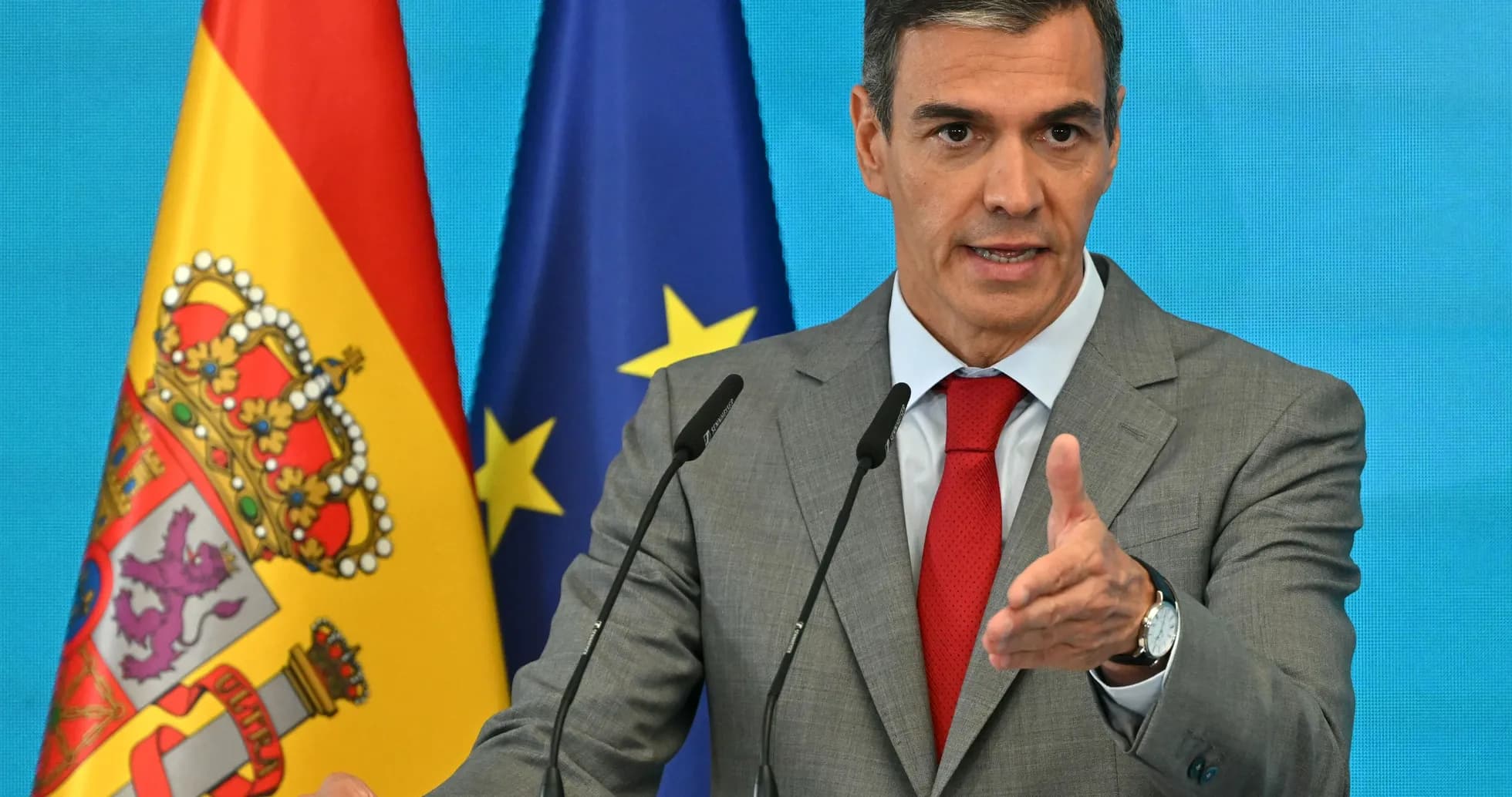 Politician speaking at a podium with flags behind Politician speaking at a podium with flags behind