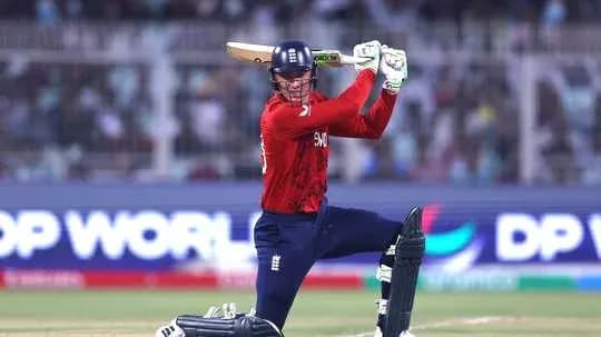 Batsman in red England kit preparing to strike ball Batsman in red England kit preparing to strike ball