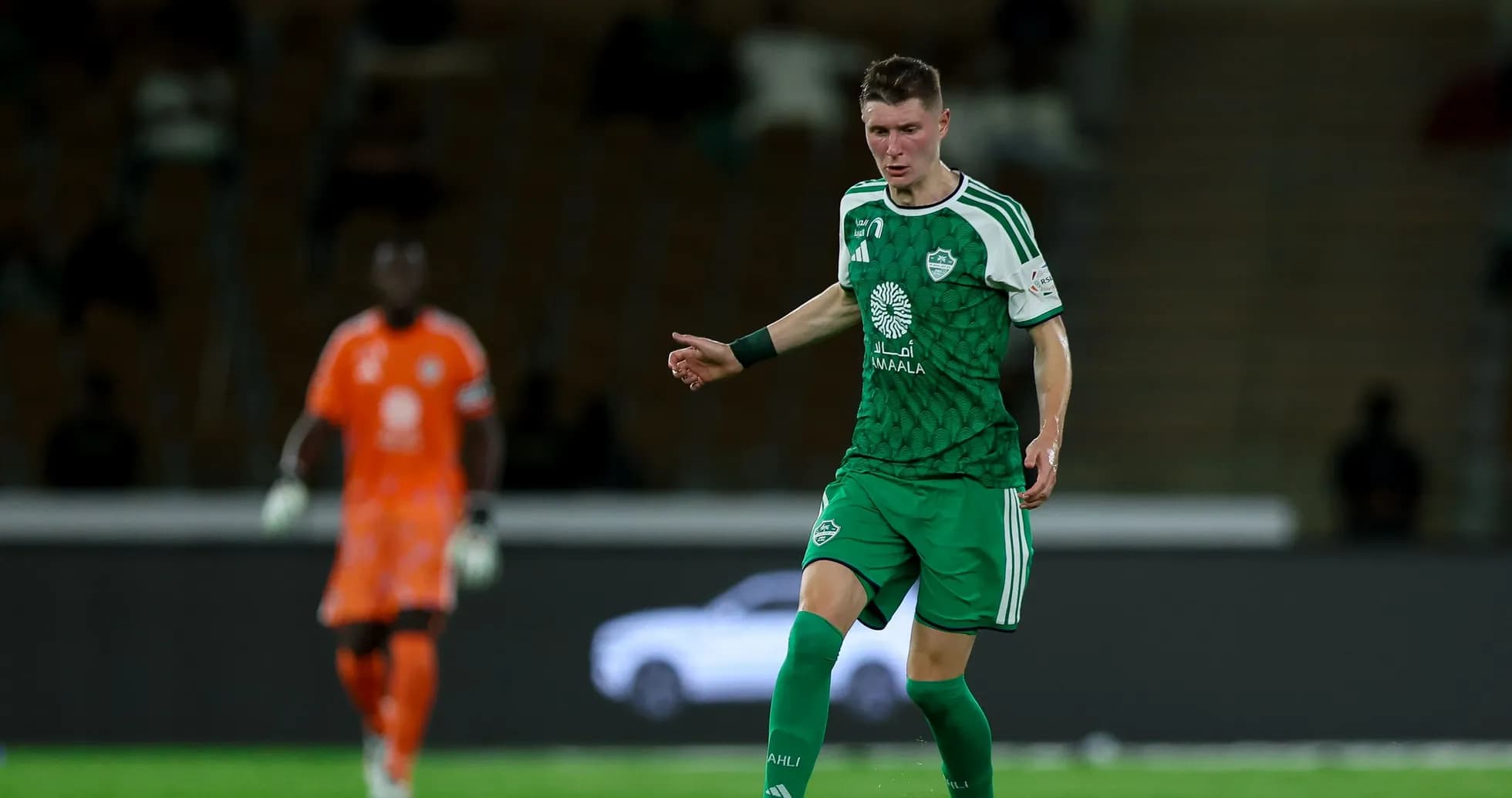Player in green kit controlling the ball on field Player in green kit controlling the ball on field