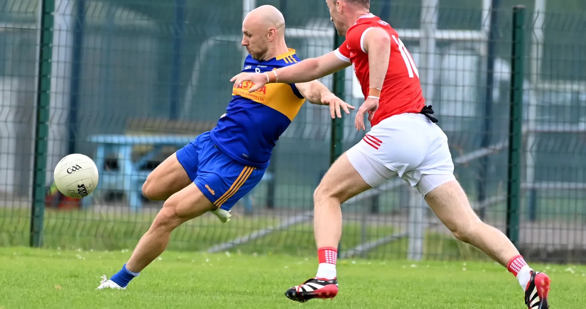 Player kicking ball while being challenged by opponent Player kicking ball while being challenged by opponent