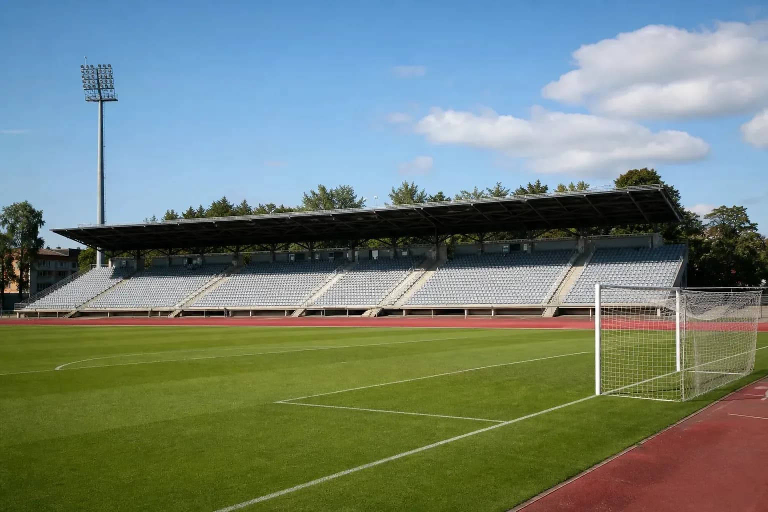 Empty stadium with green pitch and goalpost Empty stadium with green pitch and goalpost