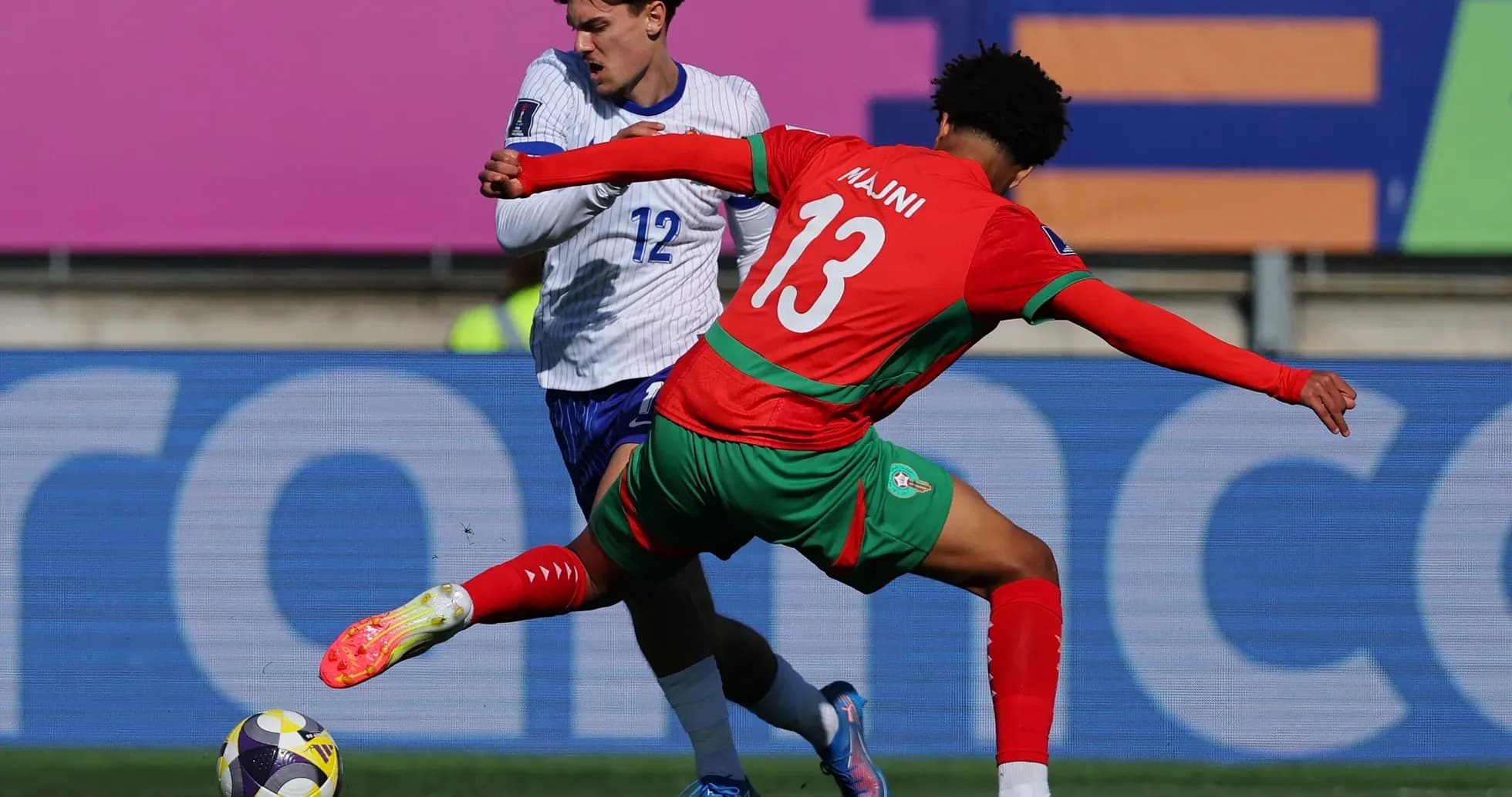 Player in red challenging opponent in blue for the ball Player in red challenging opponent in blue for the ball