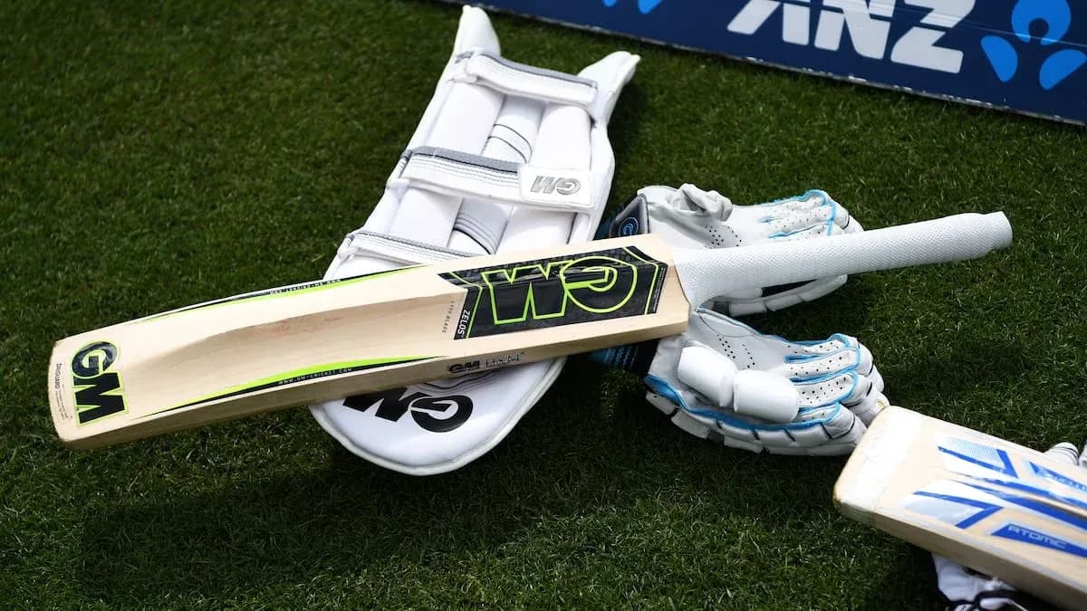 Cricket bat, gloves, and pads on grass Cricket bat, gloves, and pads on grass